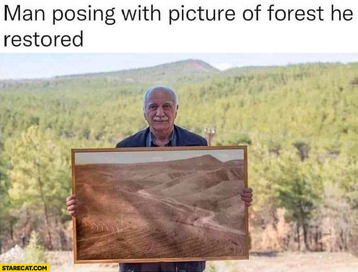 Man posing with picture of forest he restored